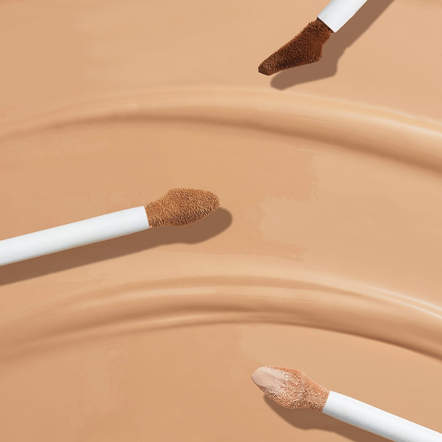 Braune Oberfläche mit drei Make-up Pinselspitzen